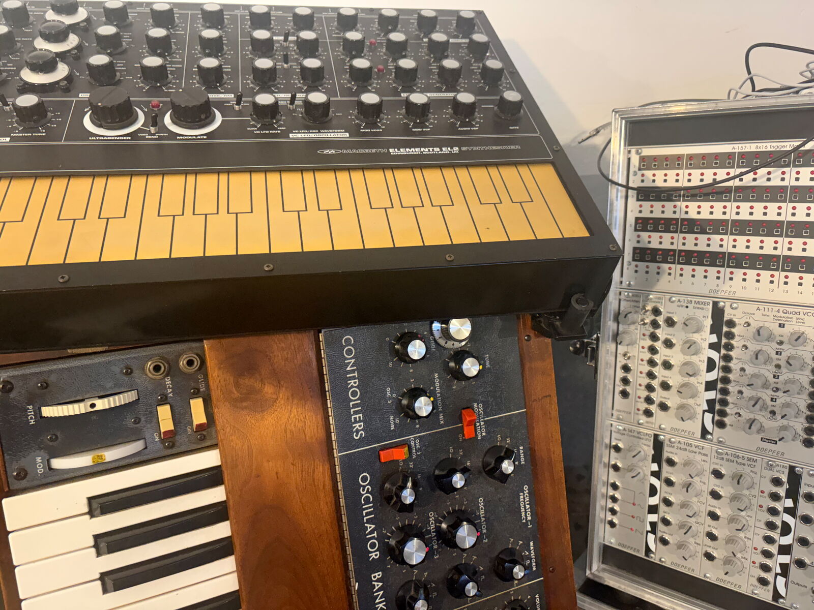 A Macbeth Elements EL2 with yellow touch keyboard, a Minimoog below it and a Doepfer A-100 modular system in a clear case